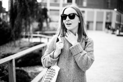 Portrait of young woman wearing sunglasses standing outdoors