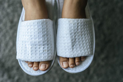 Low section of woman wearing white flip-flops