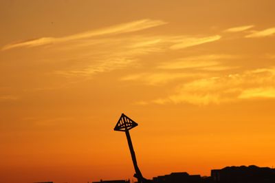 Silhouette sign against orange sky