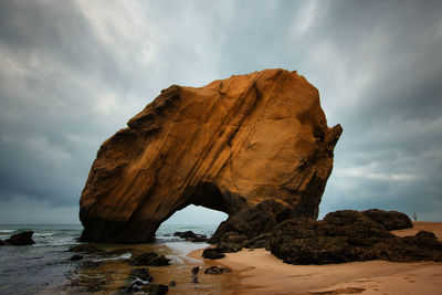 Rock formation on beach against sky