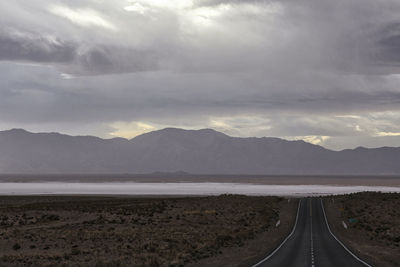 Road by mountains against sky