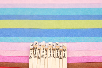 Matchsticks with faces painted on the heads on multicolored paper