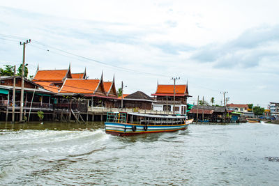 Boat moored on river by buildings against sky