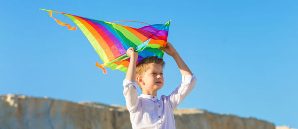 Low angle view of woman with umbrella against blue sky