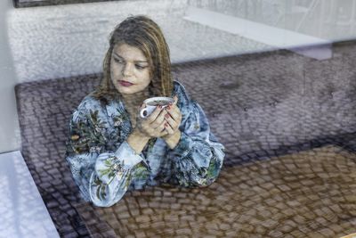 Woman holding coffee cup sitting at cafe