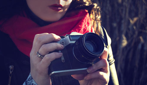 Midsection of woman using camera outdoors