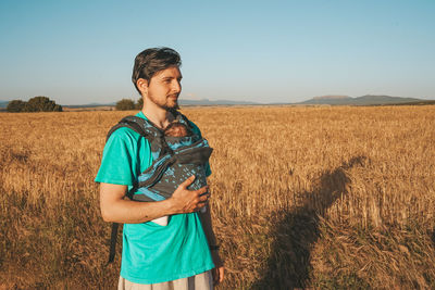 Young man standing on field against clear sky