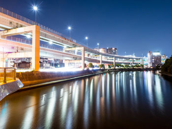 Illuminated bridge over river against sky at night