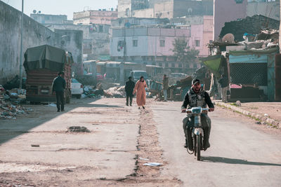 People riding bicycle on street against buildings in city