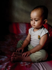 Cute baby boy sitting on bed at home