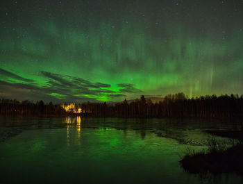 Reflection of aurora borealis in lake against sky at night