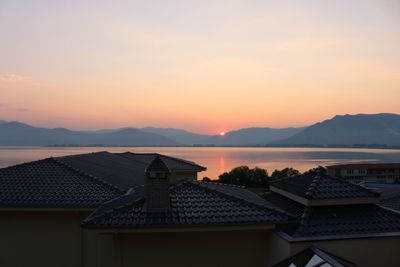 Houses and buildings against sky during sunset