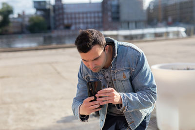 Man photographing with mobile phone while standing in city