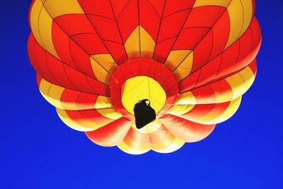 Low angle view of hot air balloon flying against clear blue sky