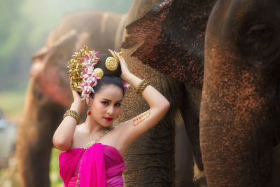 Female in traditional clothing sitting by elephants