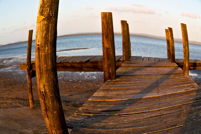 Wooden posts on beach against sky