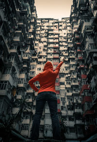 Rear view of man standing by buildings in city