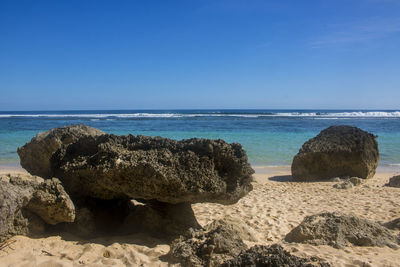 Rocks on beach against clear blue sky