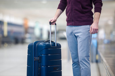 Midsection of man holding suitcase