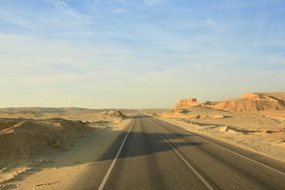Road leading towards desert against sky