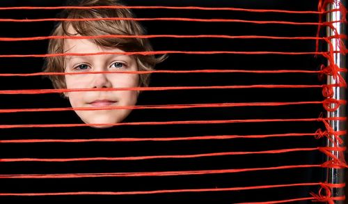 Portrait of boy seen through red threads