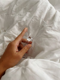 Female hand holding empty glass in bed