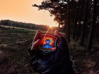 Midsection of man in field against sky at sunset