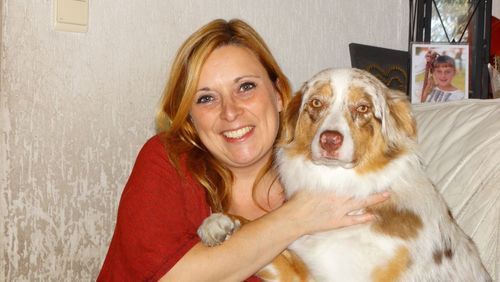 Portrait of happy woman sitting with dog on sofa