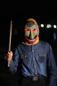 Man wearing mask while holding stick at night