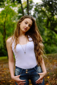 Portrait of young woman standing against trees