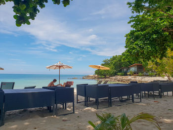 Chairs and table at beach against sky