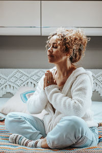 Portrait of smiling young woman sitting on bed at home