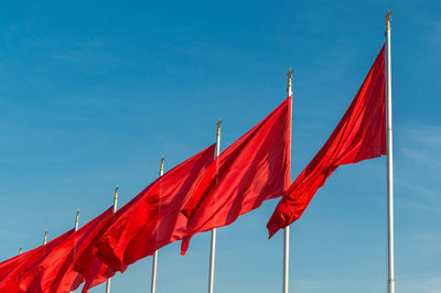 Low angle view of flags against clear blue sky