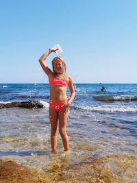 Full length of woman standing at beach against sky