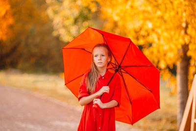 Girl holding umbrella looking away standing outdoors