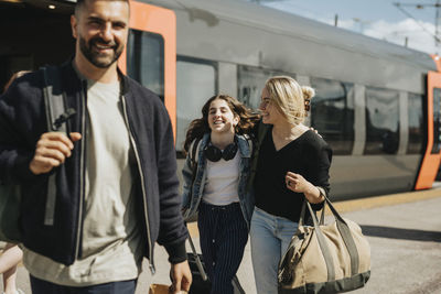 Happy family disembarking from train at station during sunny day