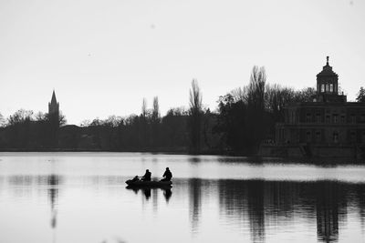 Two people in a. oat on a lake against clear sky