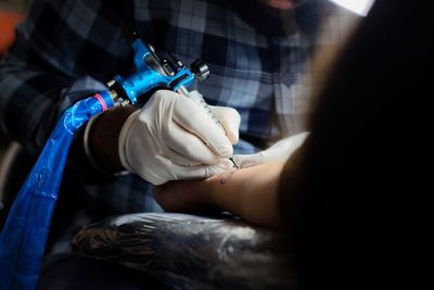 Midsection of tattoo artist making tattoo