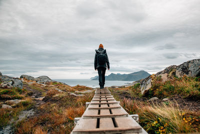 Rear view of woman walking on mountain against sky