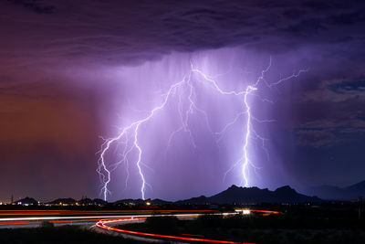 Lightning over illuminated city against sky at night