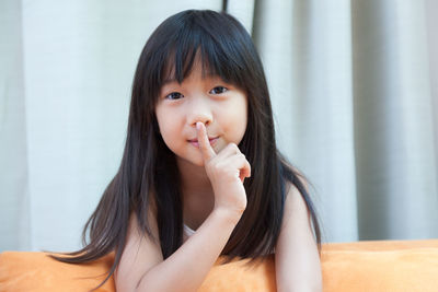 Portrait of girl with finger on lips at home