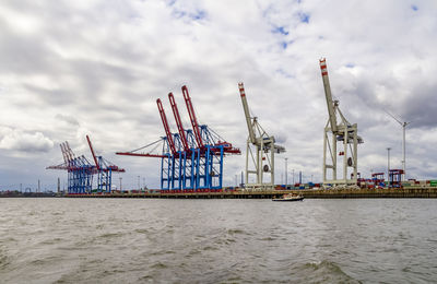 Cranes at commercial dock against sky