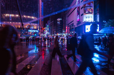 People walking on illuminated city at night