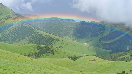 Scenic view of rainbow over land against sky