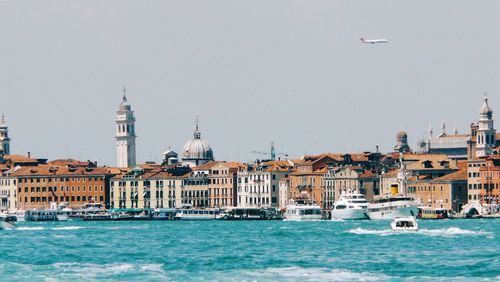 Boats in sea by city against sky