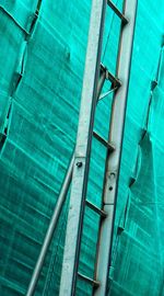 Low angle view of ladder against turquoise scaffolding