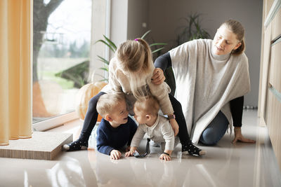 A mother with her three children playing on the floor at home