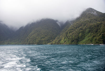 Scenic view of lake by mountains against sky