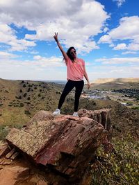 Full length of woman standing on rock against sky