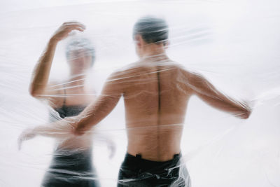 Rear view of shirtless man and woman standing outdoors